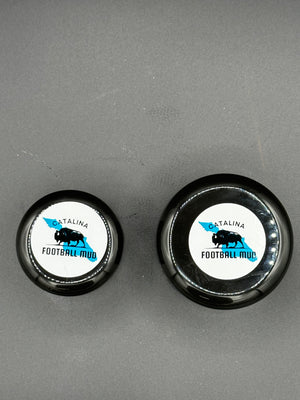 Two black bottle caps with white labels on a gray background